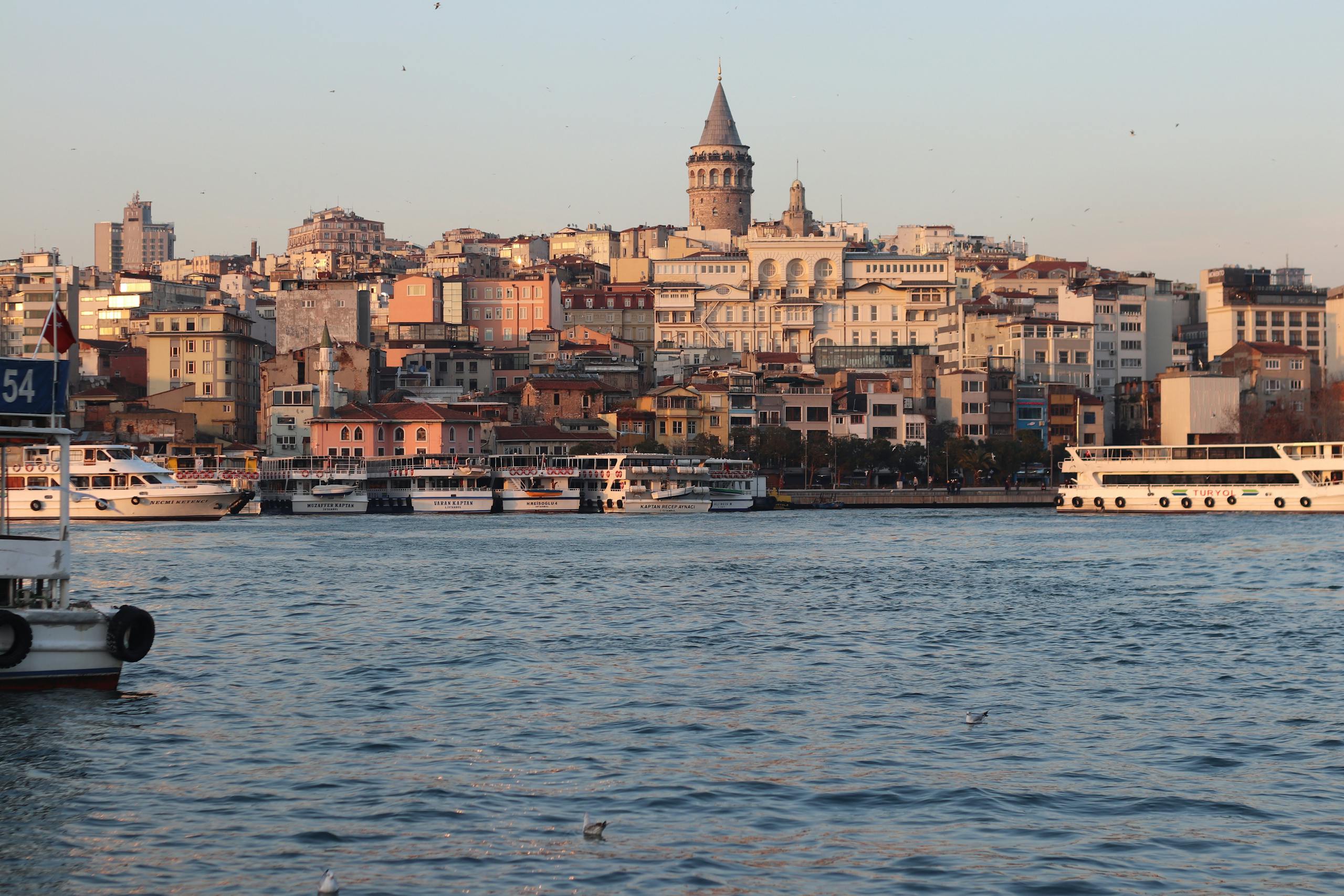 A breathtaking view of the Galata Tower and Istanbul's vibrant waterfront at sunset.