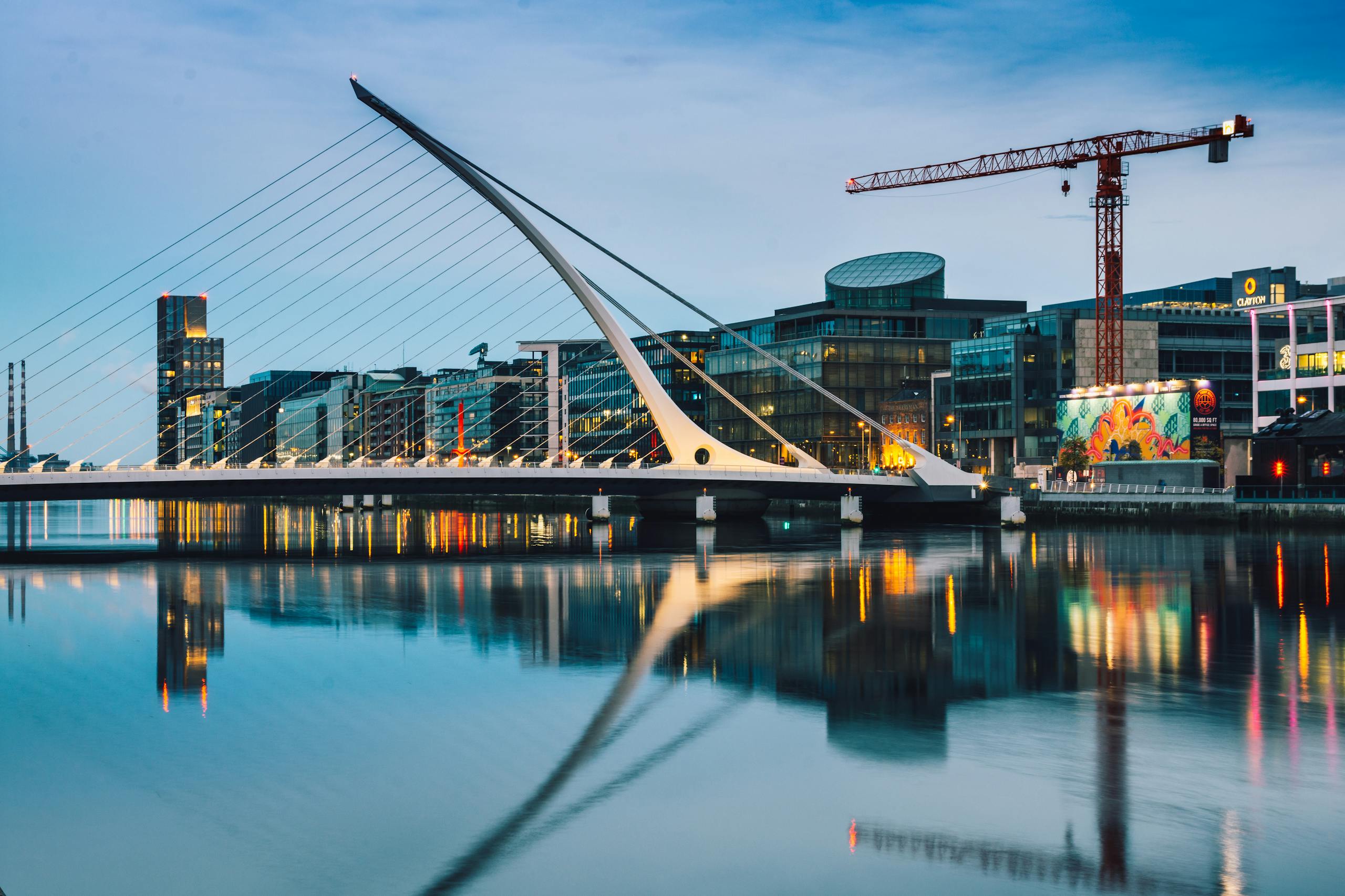 Stunning twilight view of the Samuel Beckett Bridge and Dublin skyline reflecting in the River Liffey.